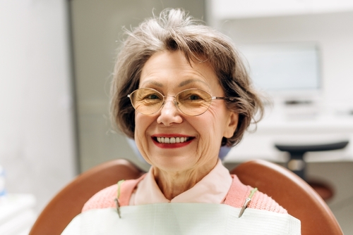 Elderly,Woman,With,Glasses,Smiling,While,Seated,In,A,Dental